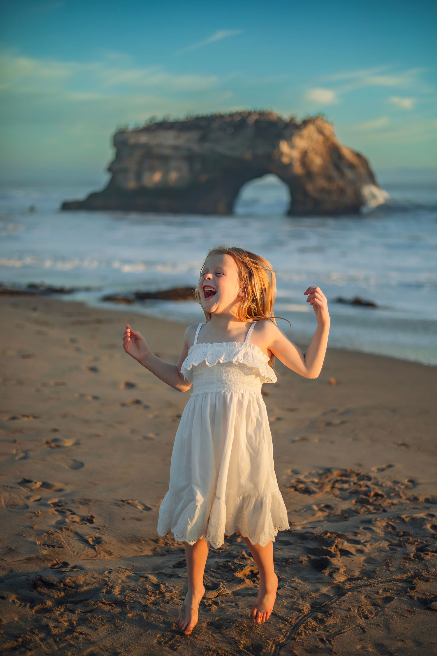 A girl playing at the beach in Santa Cruz during golden hour, captured in natural light with candid, joyful moments and coastal scenery.