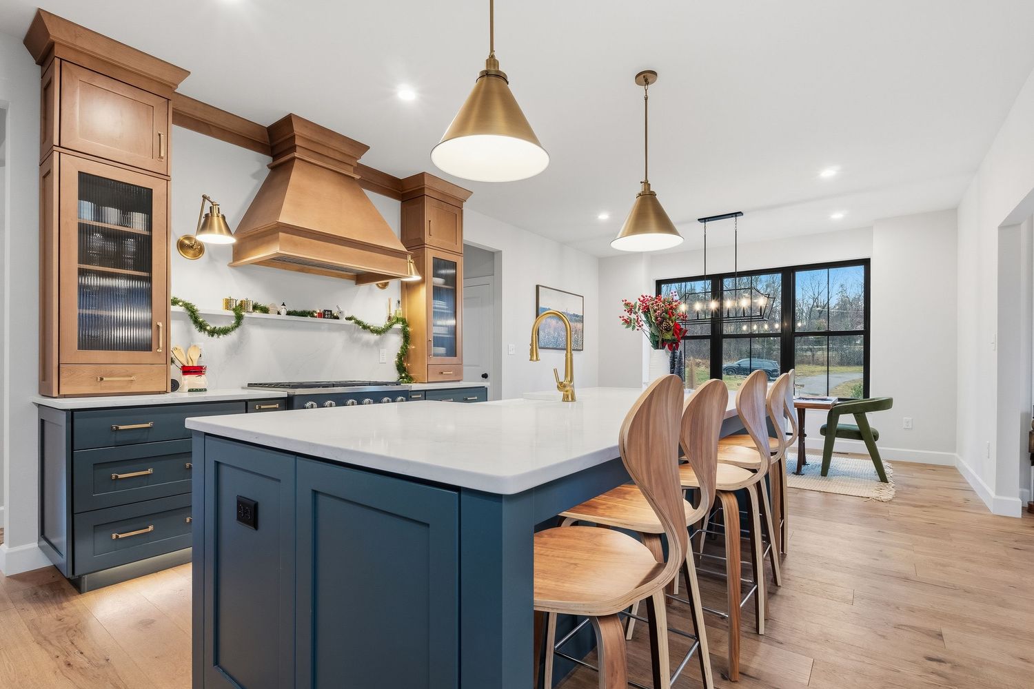 Modern kitchen with large island, seating, custom cabinetry, pendant lighting, and hardwood flooring, photographed for real estate marketing