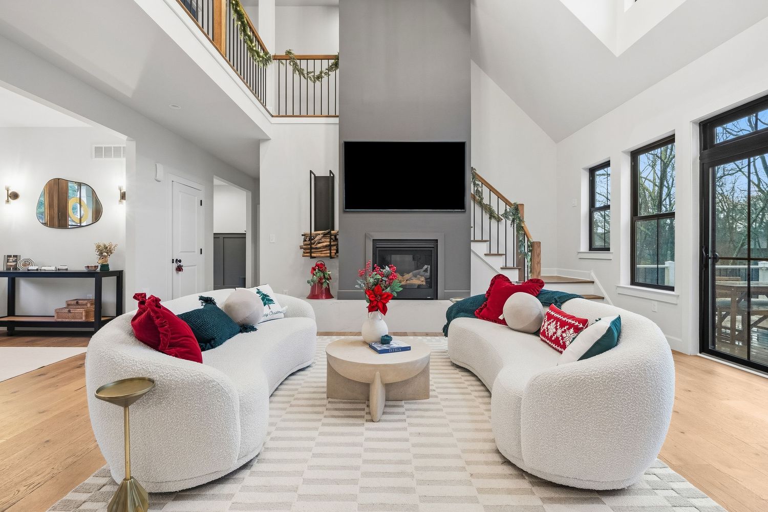 Bright living room with modern seating, fireplace feature, hardwood floors, and large windows, photographed for residential real estate list