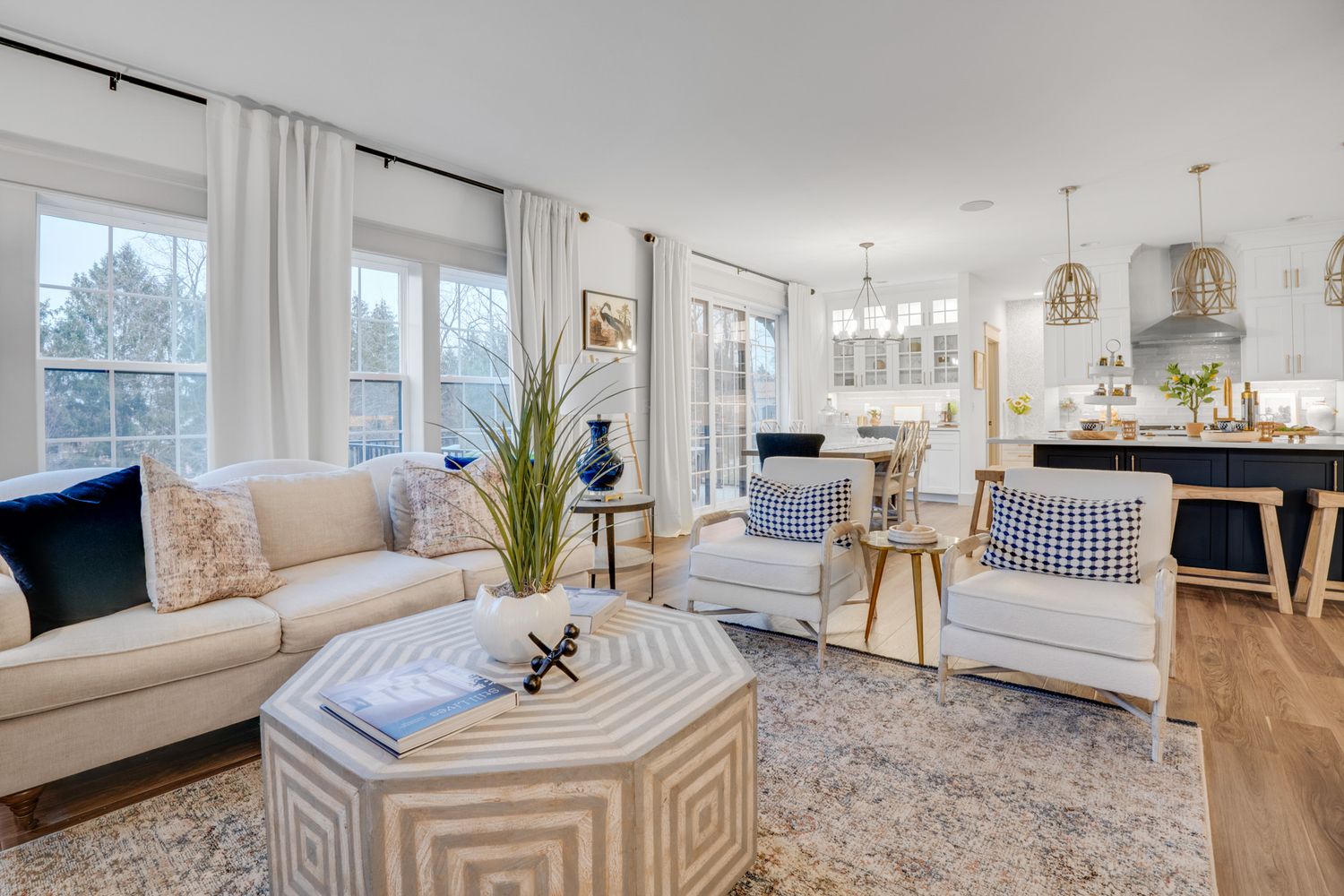 Open-concept living and kitchen area with large windows, modern seating, hardwood floors, and natural light, photographed for real estate ma