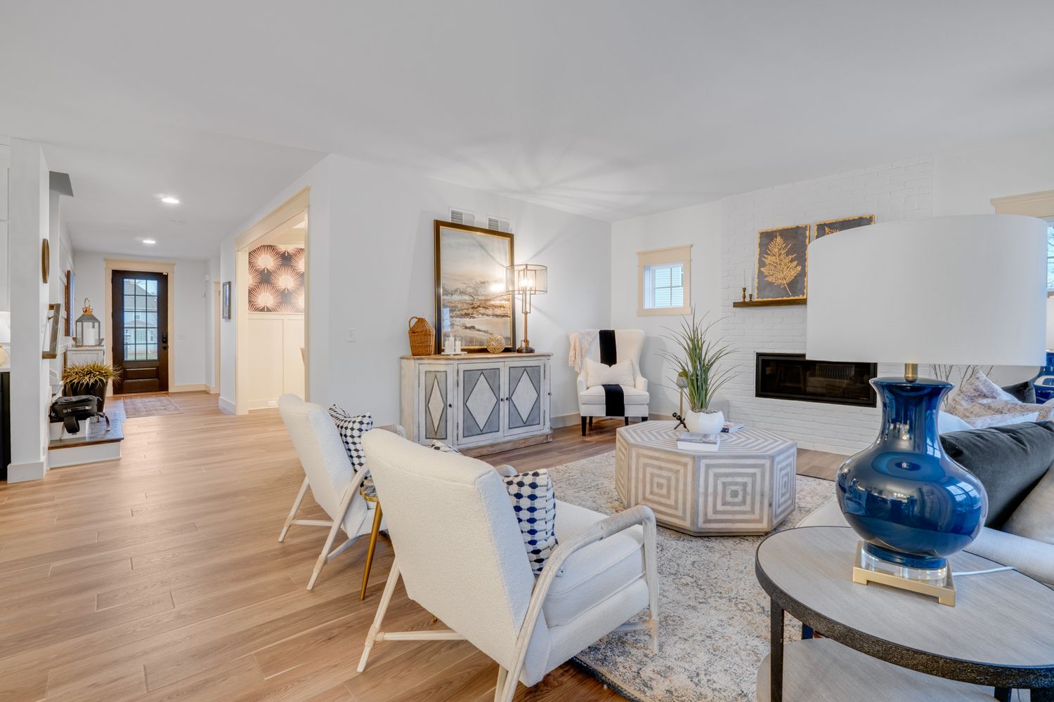 Open living and dining area with hardwood floors, modern seating, neutral decor, and natural light, photographed for real estate listing