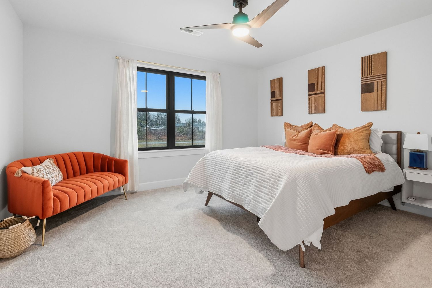 Spacious bedroom with neutral decor, ceiling fan, large window, and modern furnishings, photographed for residential real estate listing