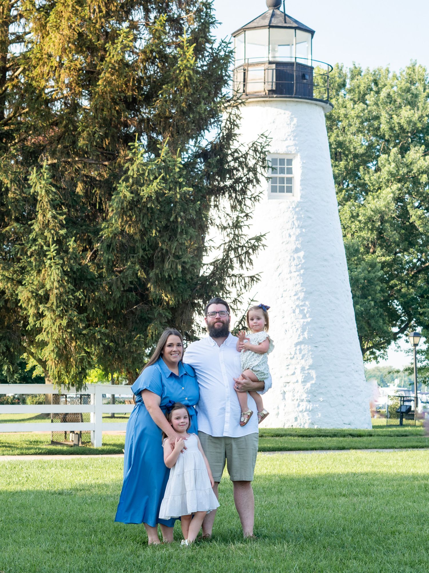 Family of four standing in front of Concord Point Lighthouse during a family photo session in Havre de Grace, MD