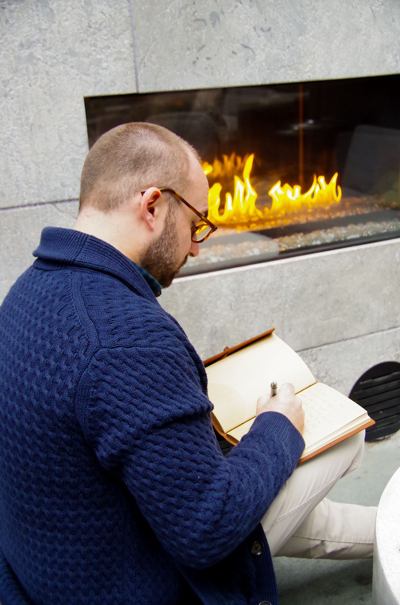 Branding business photo of man journaling in front of a fire in Fells Point, MD
