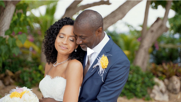 A joyful couple shares an intimate moment on their wedding day outdoors, bride in strapless gown, groom in blue suit.