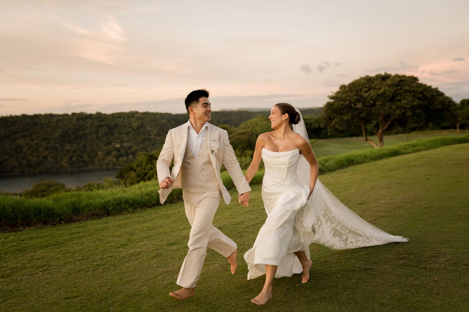 Bride and groom running hand in hand through tropical scenery during a luxury destination wedding in Hotel Andaz, Papagayo, Costa Rica.