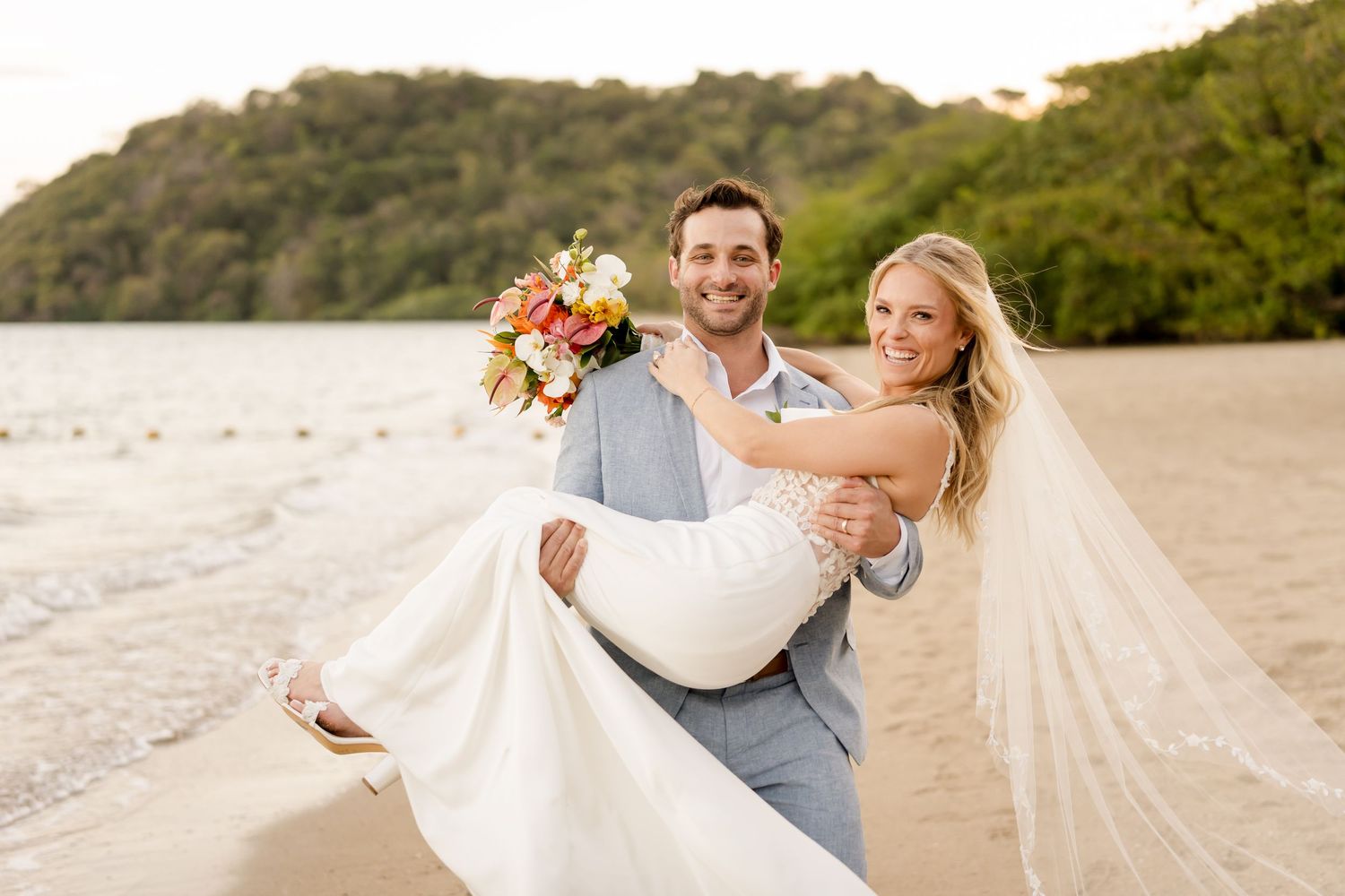 Joyful newlyweds celebrating on a tropical beach after their luxury destination wedding in Costa Rica.