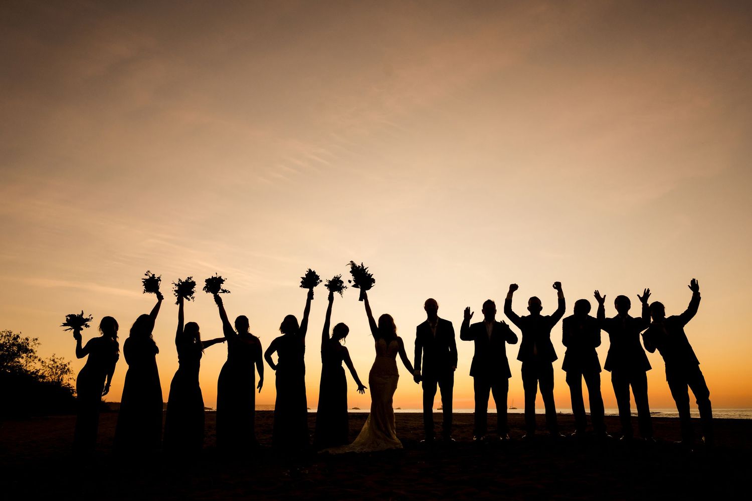 Bridal party celebrating together in a dramatic sunset silhouette during a luxury destination wedding in Guanacaste, Costa Rica.