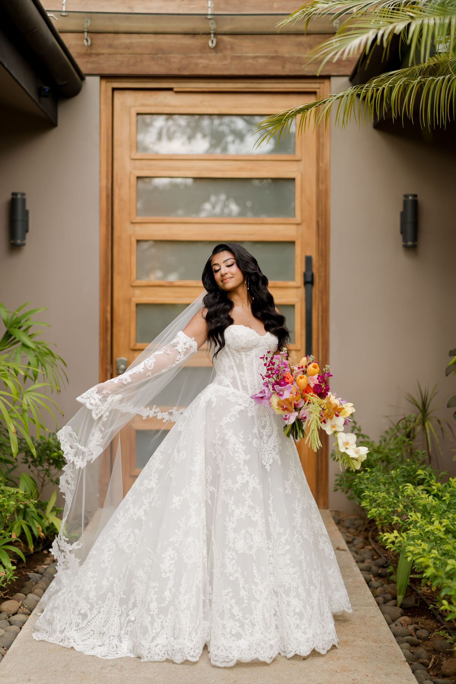 Bride wearing an intricately embroidered lace wedding gown with a colorful tropical bouquet in a luxury villa in Hacienda Pinilla Guanacaste