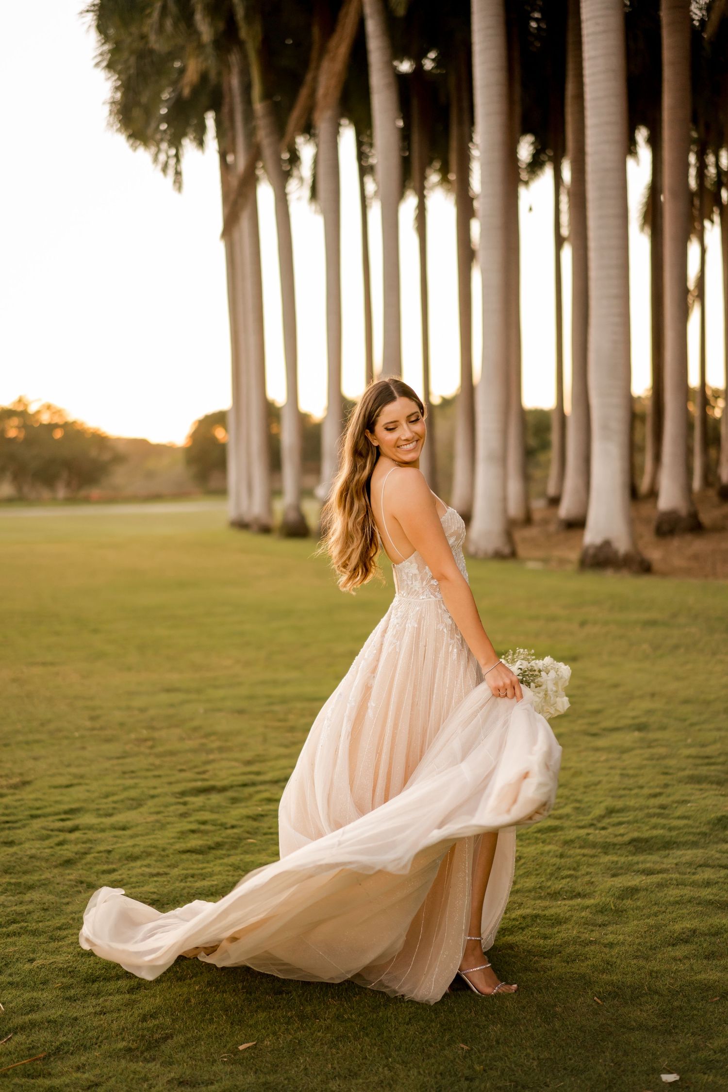 Editorial bridal portrait featuring a flowing wedding gown captured in motion during golden hour with palm trees in Papagayo, Costa Rica.