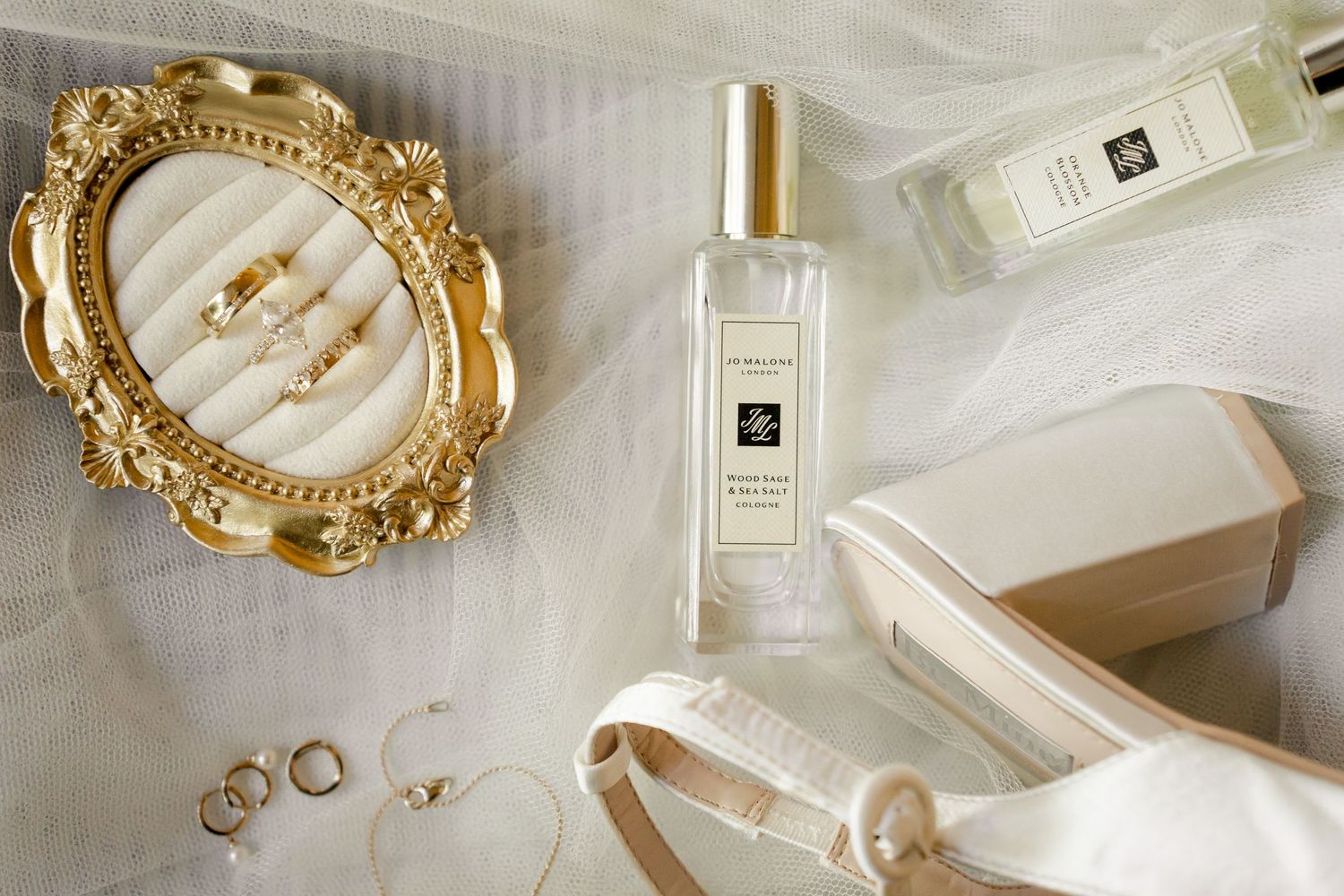 Editorial bridal flat lay featuring wedding rings, perfume, invitation suite, and luxury bridal accessories.