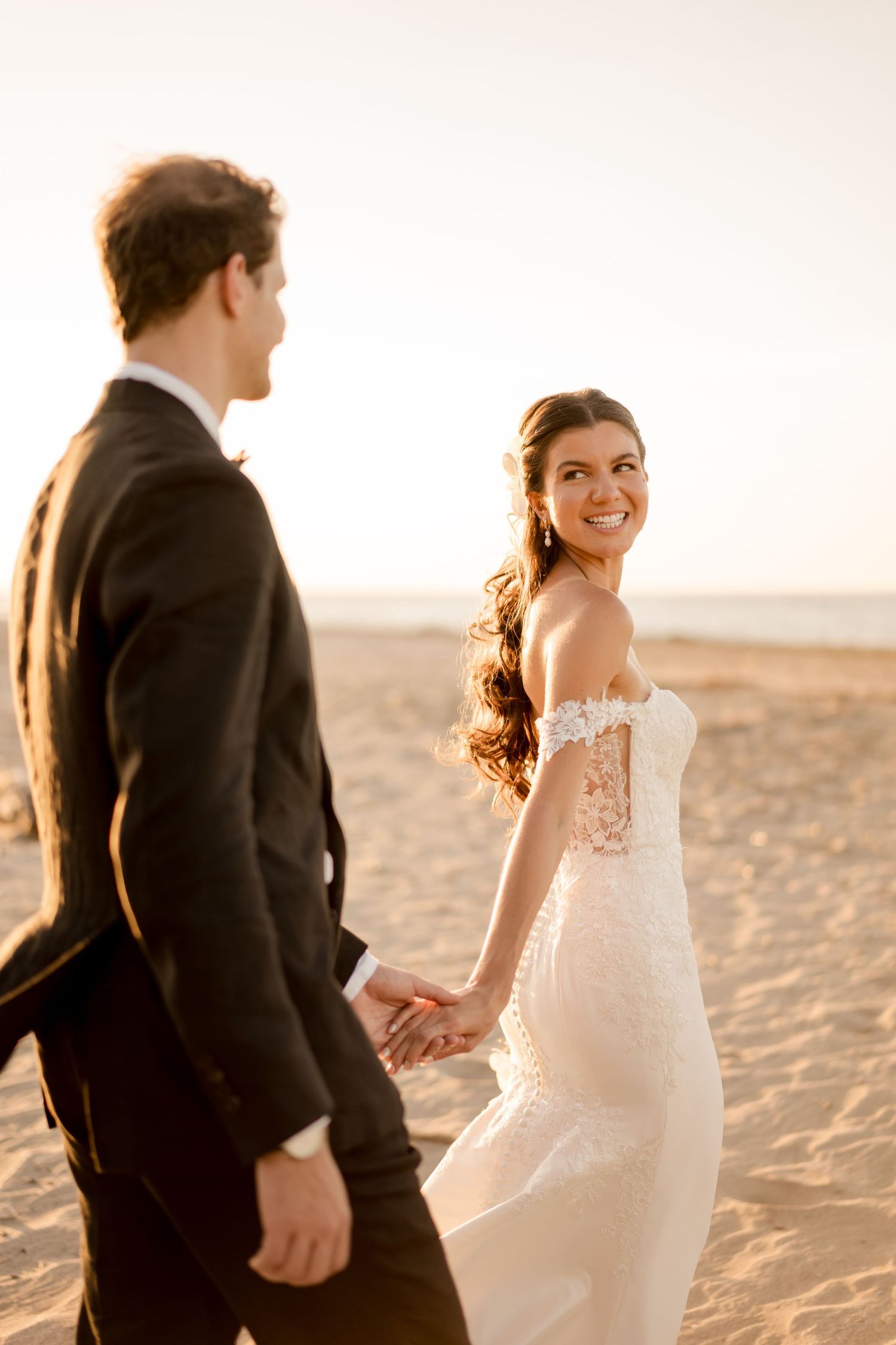 Couple walking hand in hand along a sandy beach during golden hour, capturing the joy of a sunset wedding portrait in Tamarindo, Costa Rica.