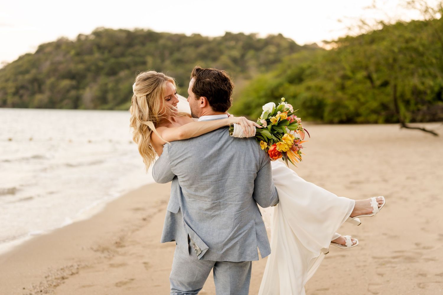 Groom carrying his bride along a secluded beach during a romantic destination wedding in Guanacaste, Costa Rica.