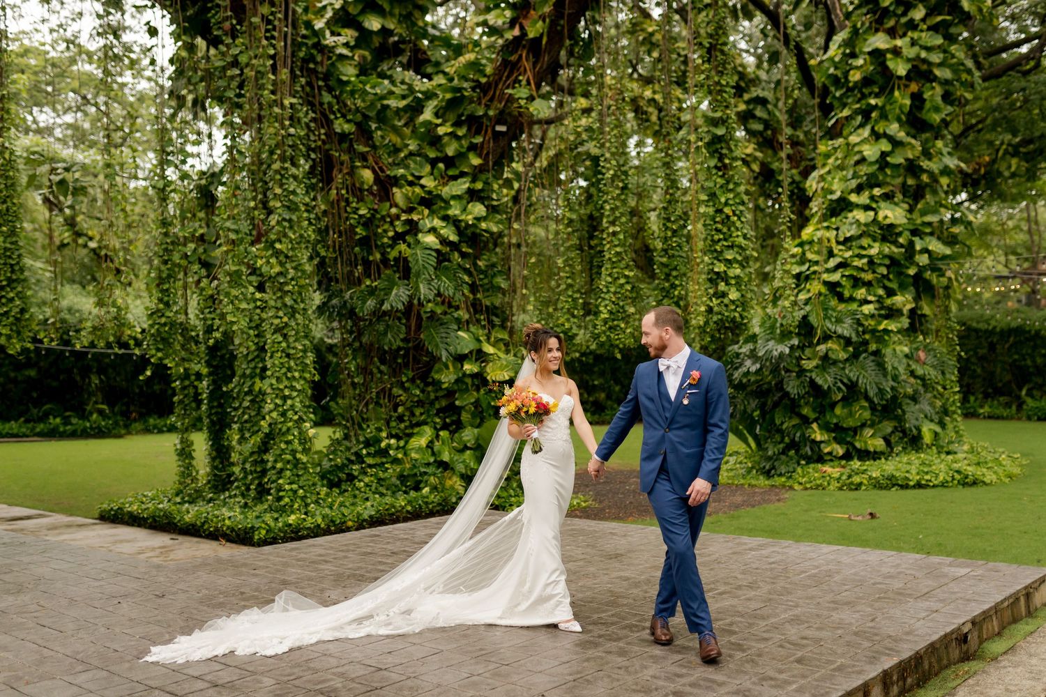 Elegant newlyweds strolling through lush tropical gardens of Mangrove Hotel in Guanacaste during a luxury destination wedding celebration.