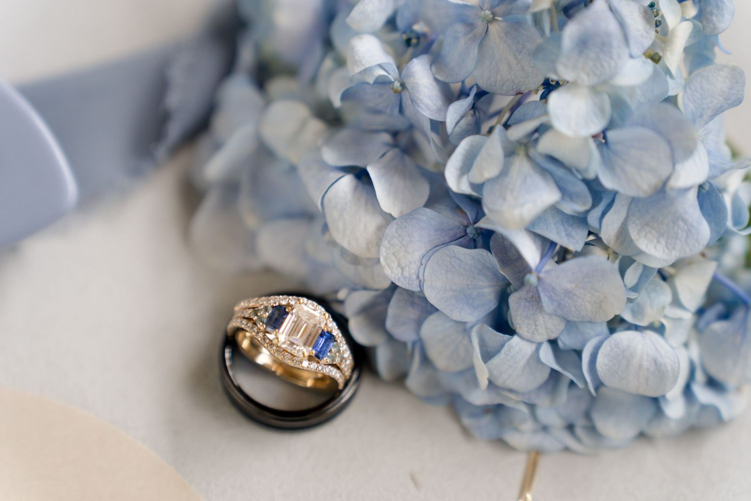 Wedding bands resting beside delicate blue hydrangeas as part of an elegant destination wedding detail collection.