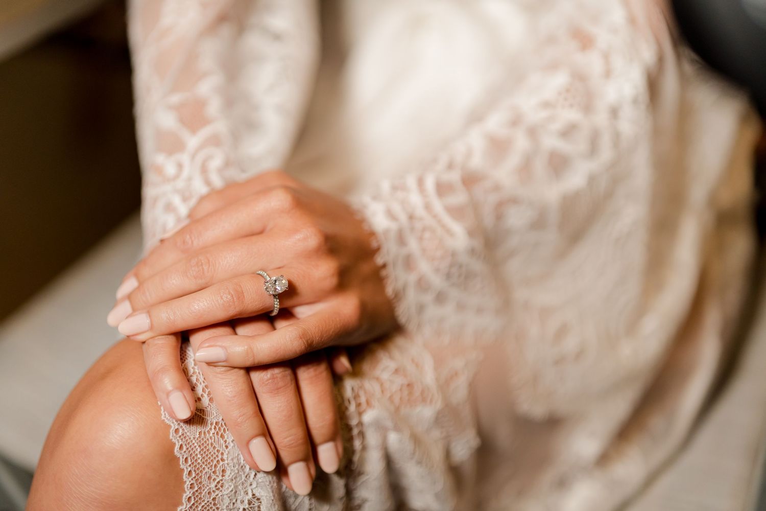 Diamond engagement ring resting on a bride's hand, highlighting timeless bridal jewelry and delicate lace wedding details.