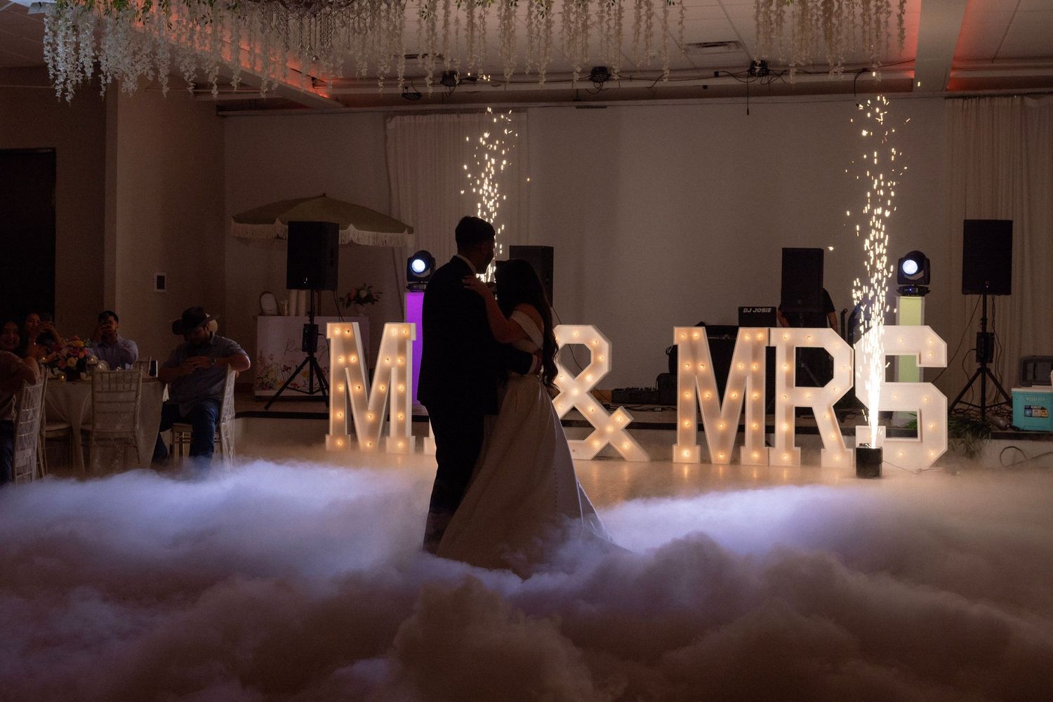 Couple shares first dance surrounded by fog machine effects before illuminated MR & MRS marquee letters.