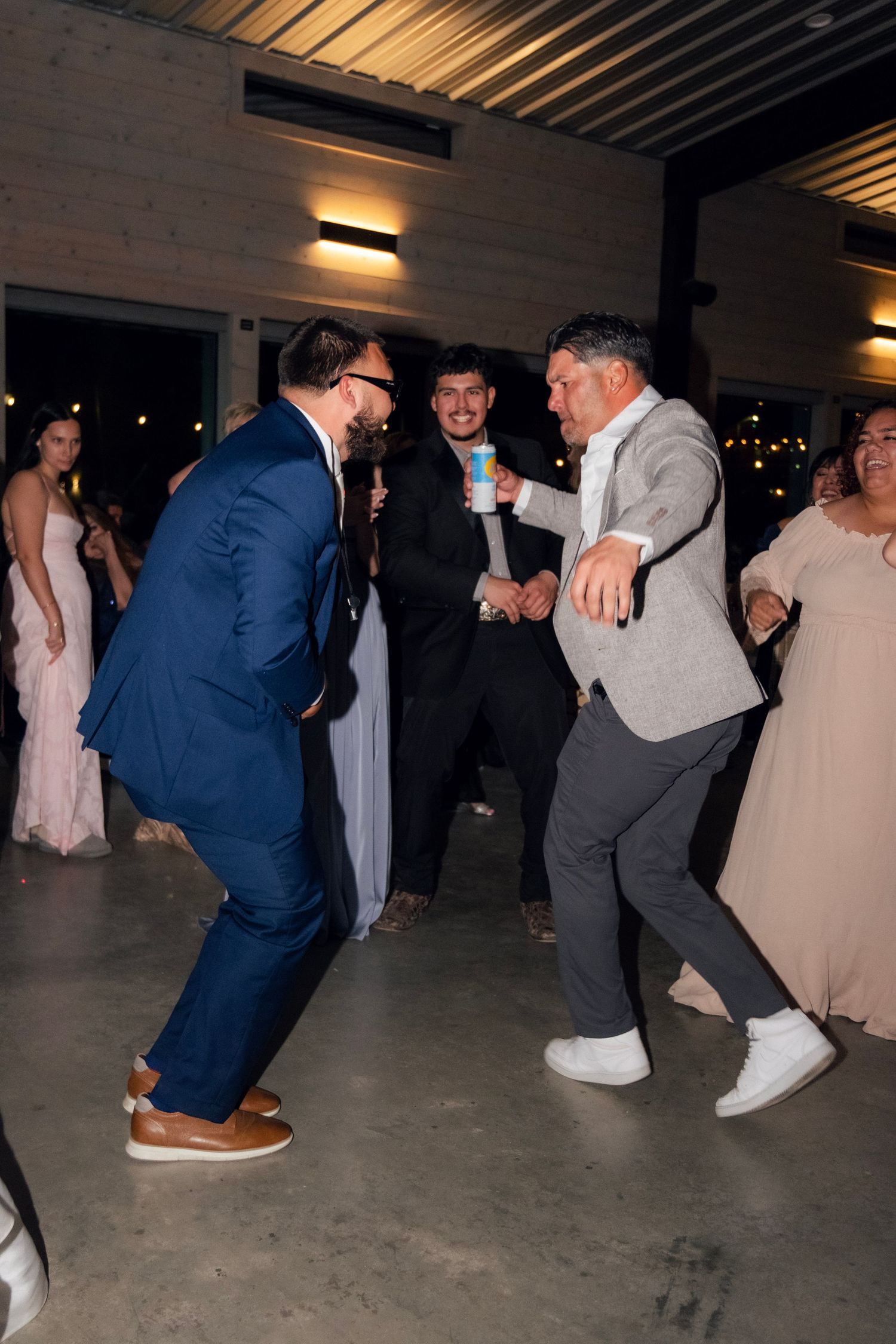 Men in formal attire dancing energetically at a wedding reception celebration.