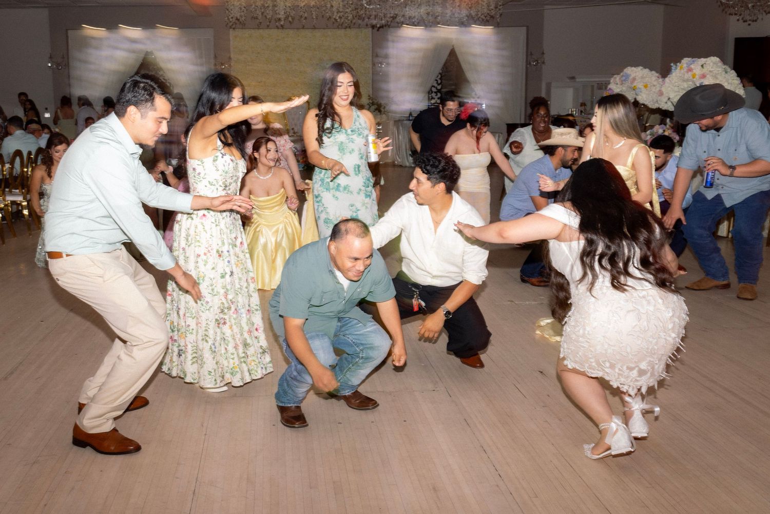 Lively wedding reception dance floor with guests performing traditional Latin dance moves together.