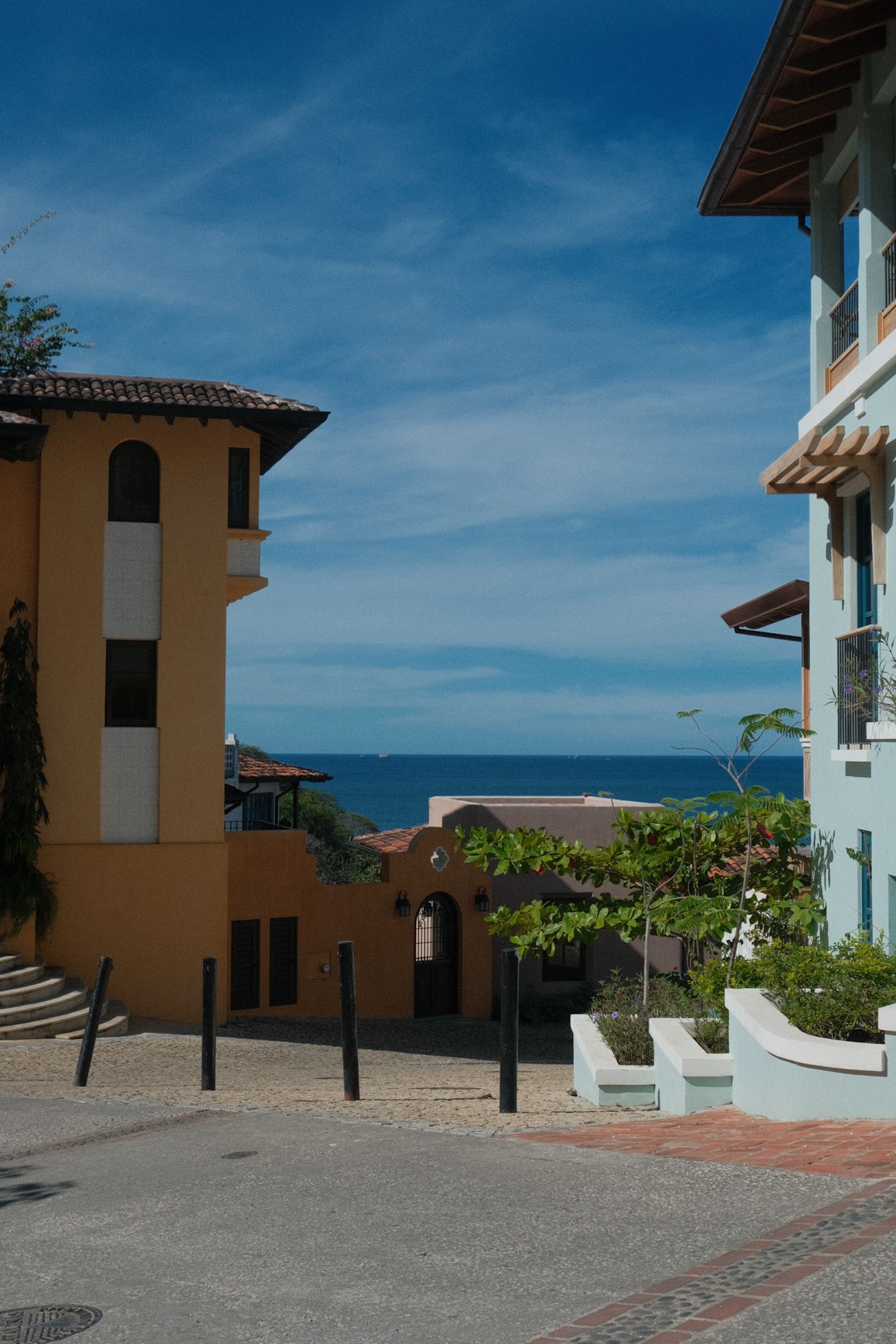 Colorful Mediterranean-style buildings frame a scenic ocean view under blue skies in a coastal resort town. Coast Rica in European inspired.
