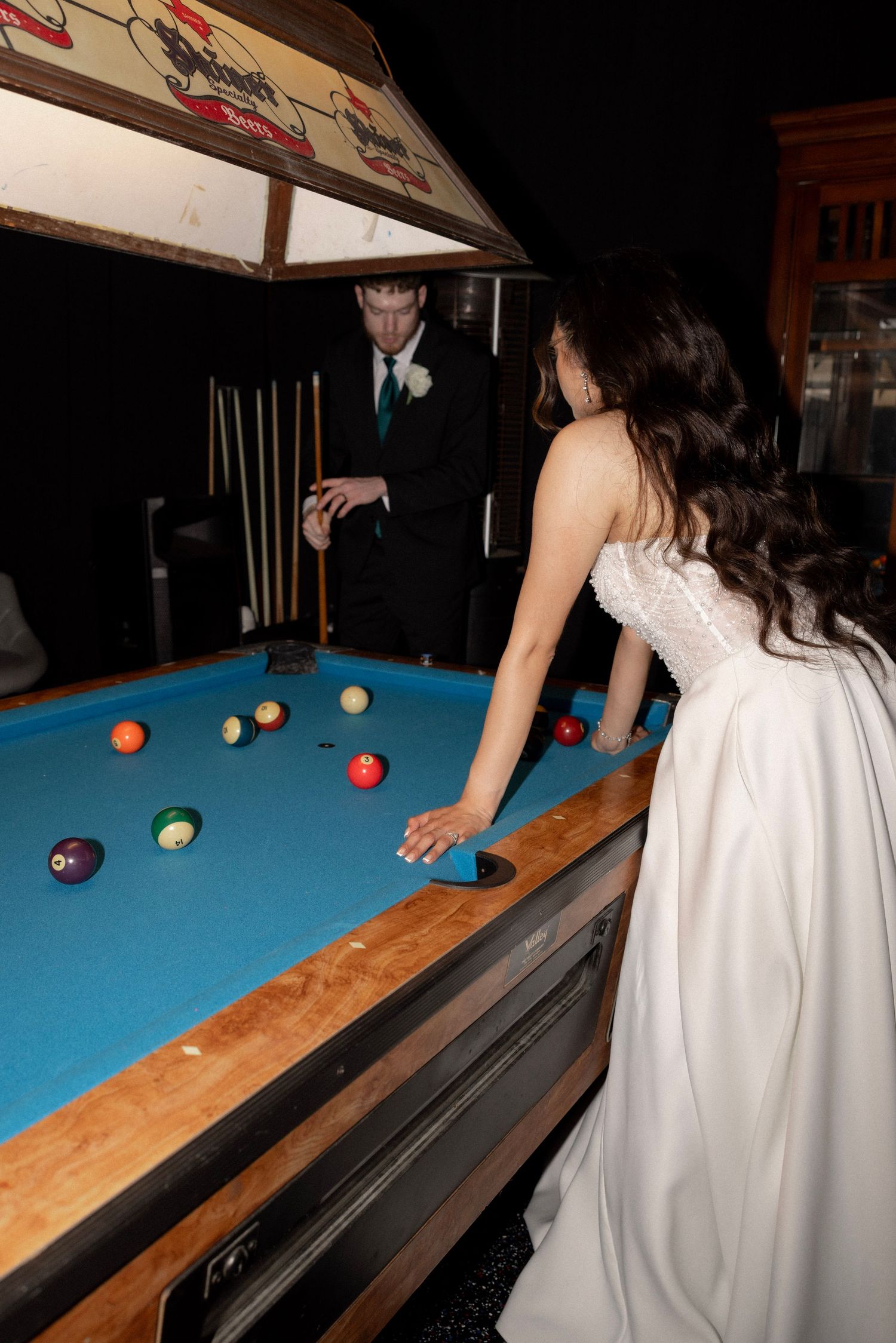 Bride and groom play pool together at their wedding reception venue.