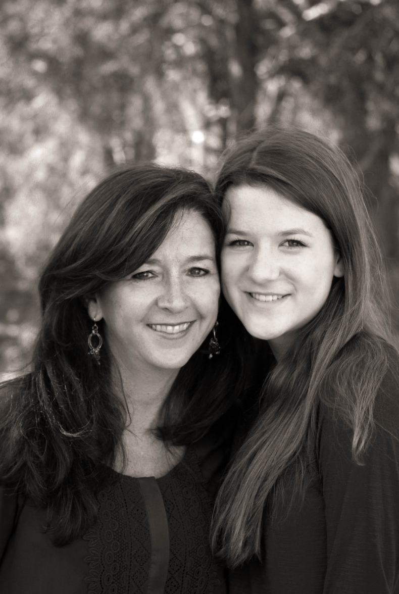 Black and white portrait of a mother and teenage daughter smiling together outdoors.