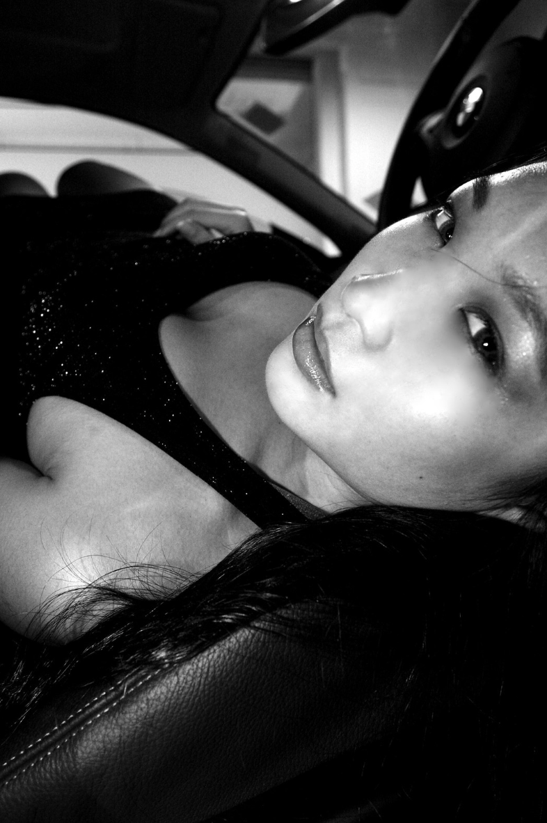 Black and white photo of a woman reclining in a car interior.