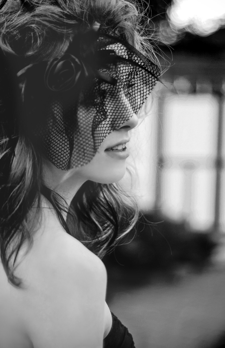 Black and white profile of a woman wearing a decorative lace eye mask.
