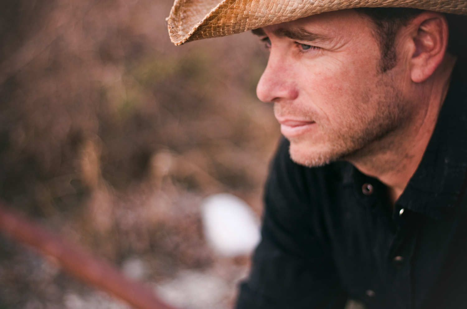 Side profile of a man in a cowboy hat looking into the distance.
