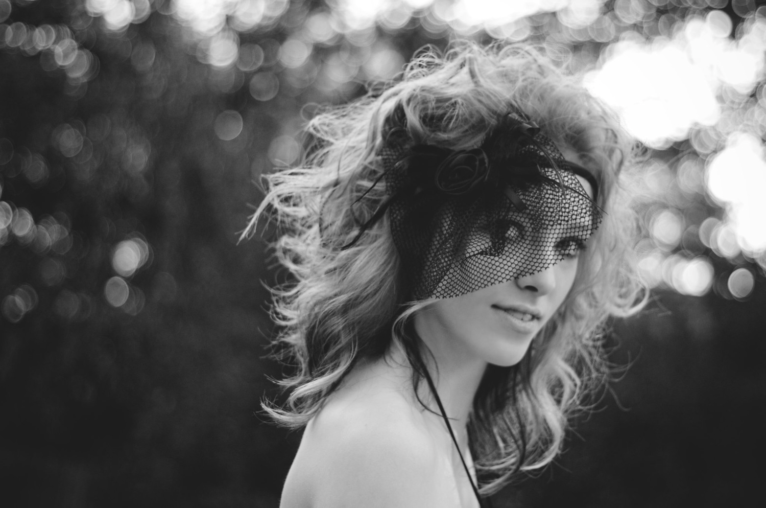 Black and white portrait of a smiling woman with windswept curly hair.