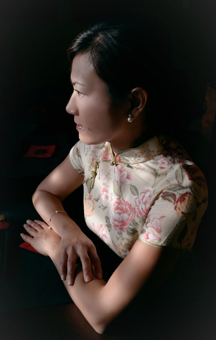 Elegant Asian woman in floral cheongsam qipao dress photographed in dramatic side profile lighting.