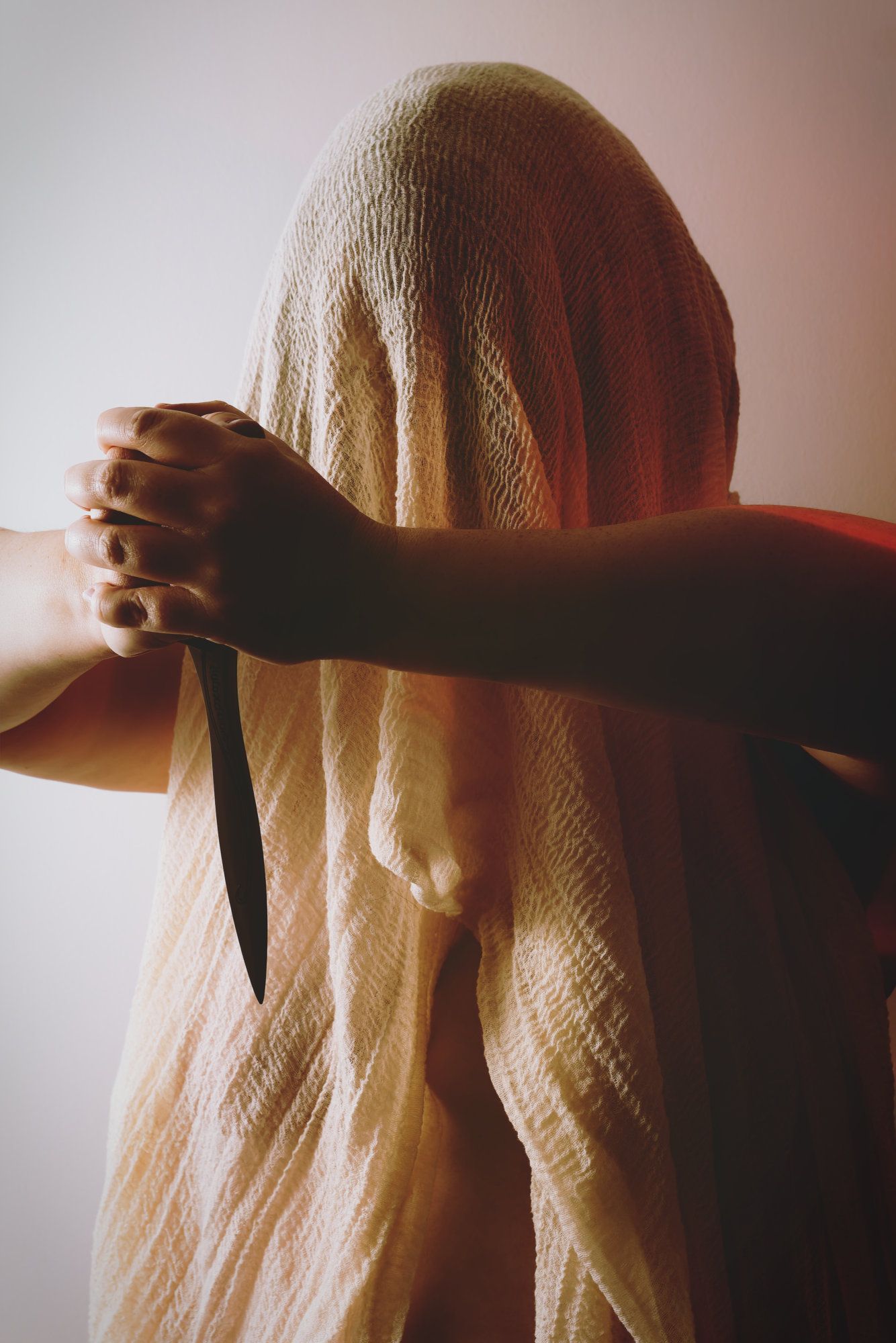 Fantasy photo of person with a veil covering their face holding a knife.