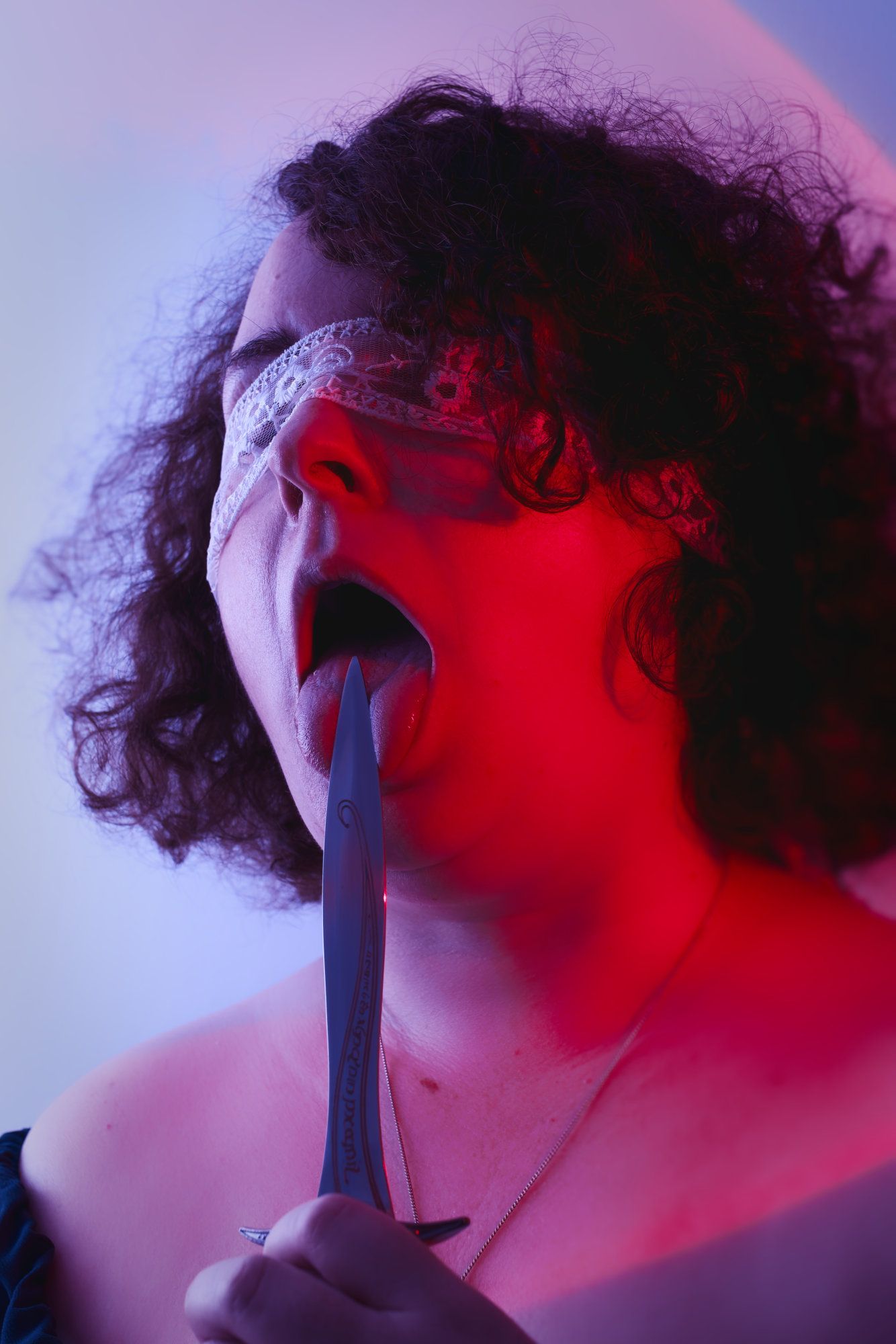Fantasy photo of person holding a knife to their tongue.