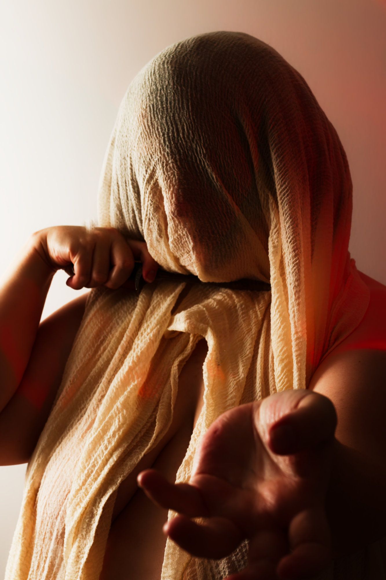 Fantasy photo of person with a veil covering their face holding a knife to their neck.