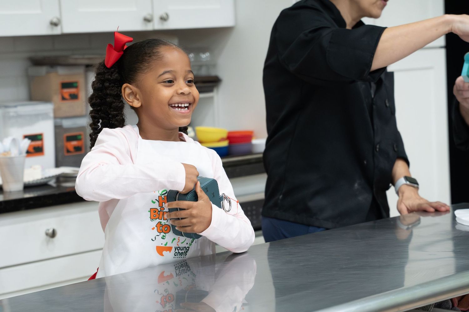Cheerful young girl laughs while standing at a kitchen counter during a birthday celebration.