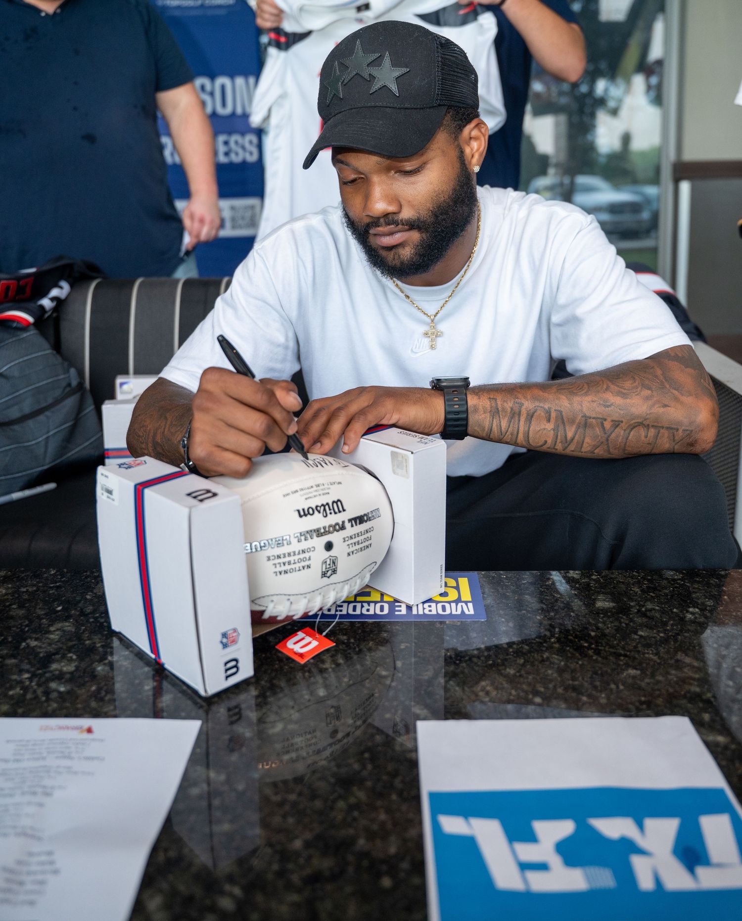 Male athlete signs autograph on football at public signing event. bratcher photography and houston photographer
