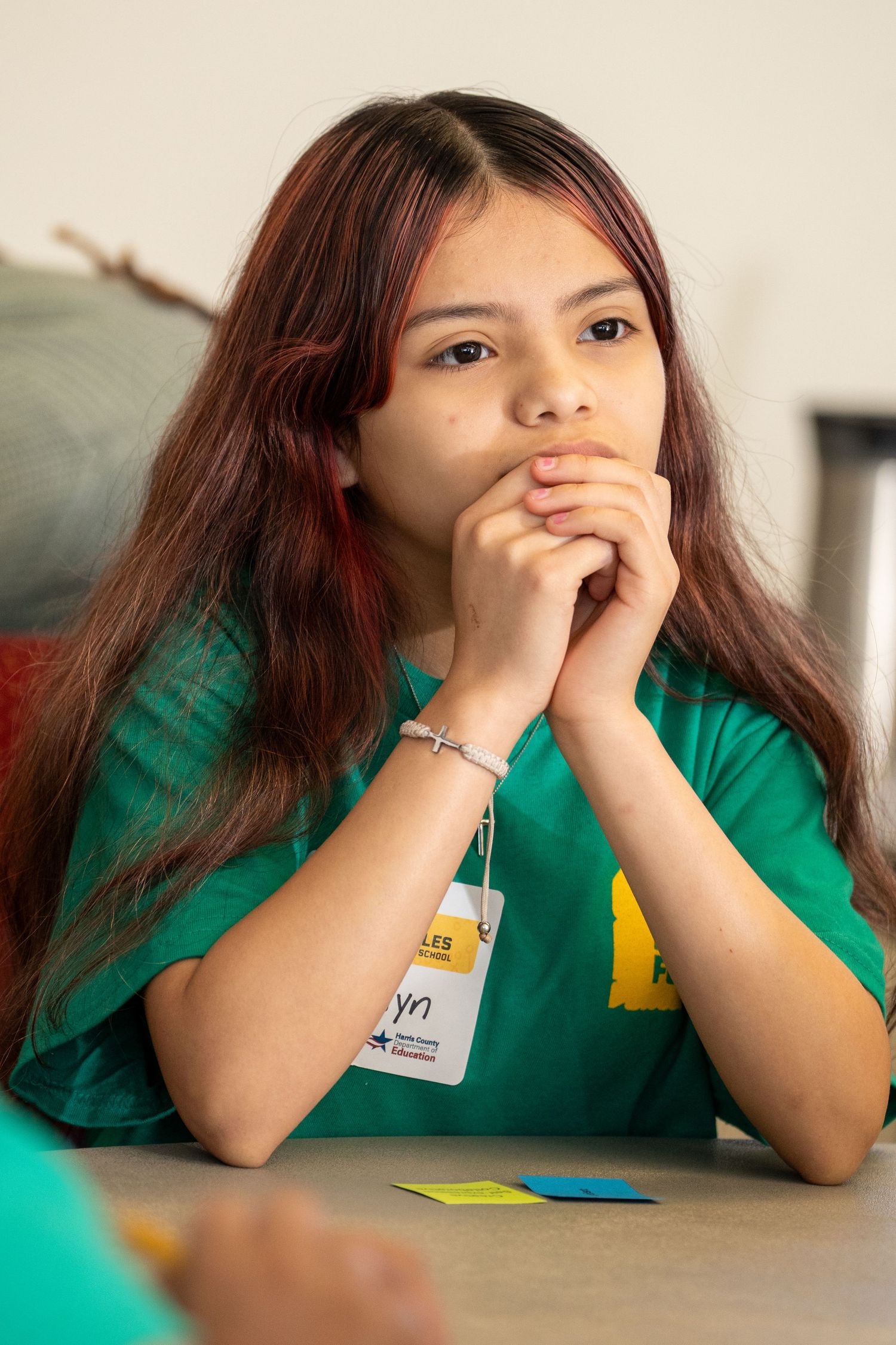Focused young girl in green t-shirt listens attentively during a youth learning program session.