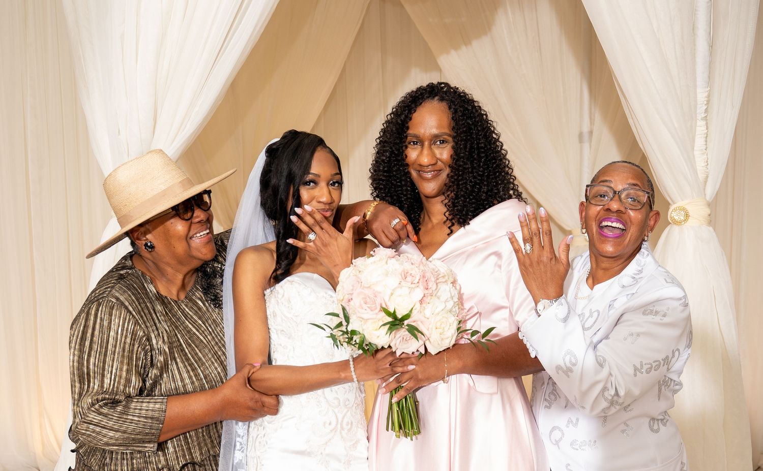 Bride posing with three generations of family women at wedding ceremony altar backdrop.