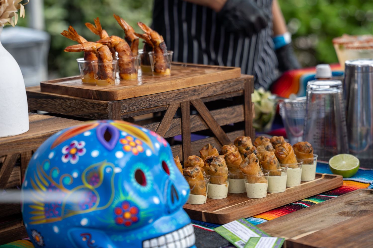 Blue sugar skull decorates Mexican cuisine booth with shrimp appetizers and stuffed bites display.