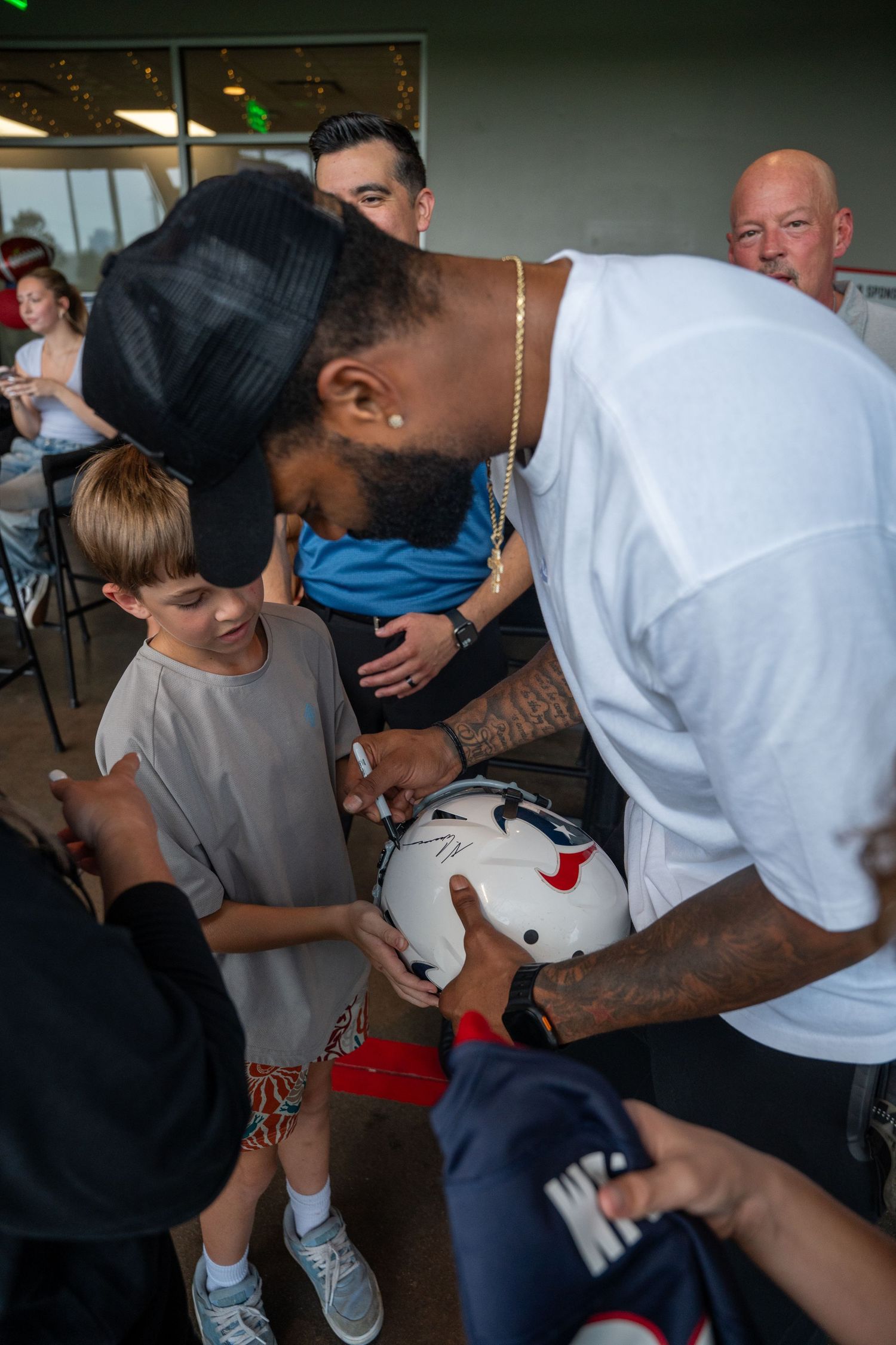 Football player signing autograph on helmet for young fan at meet and greet.
