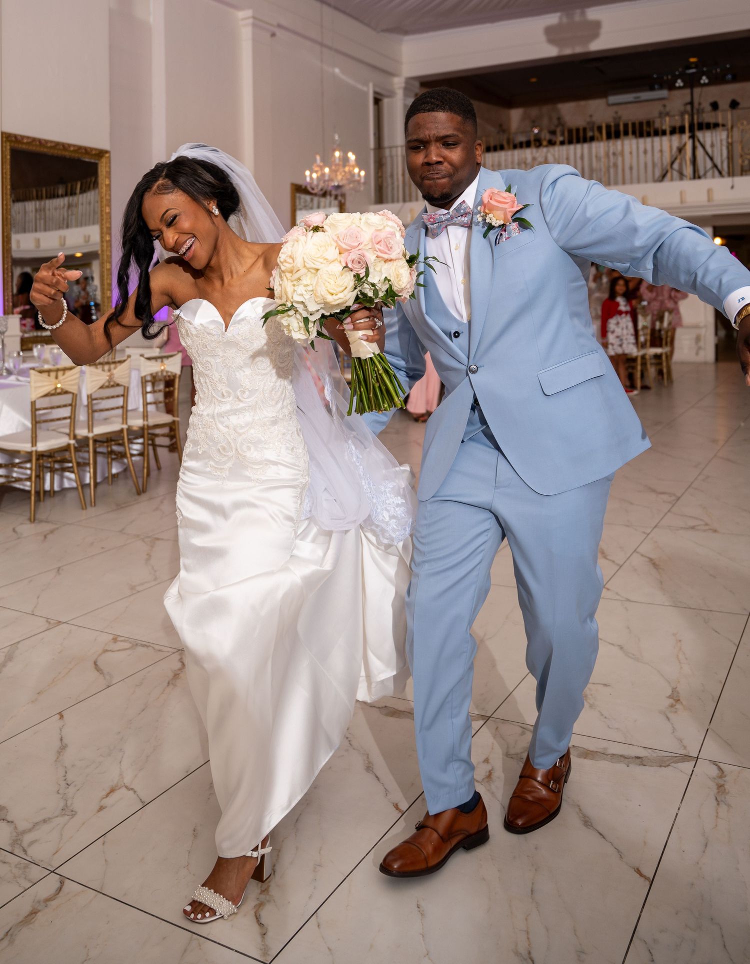 Joyful newlyweds dancing and celebrating at their wedding reception on a marble dance floor.