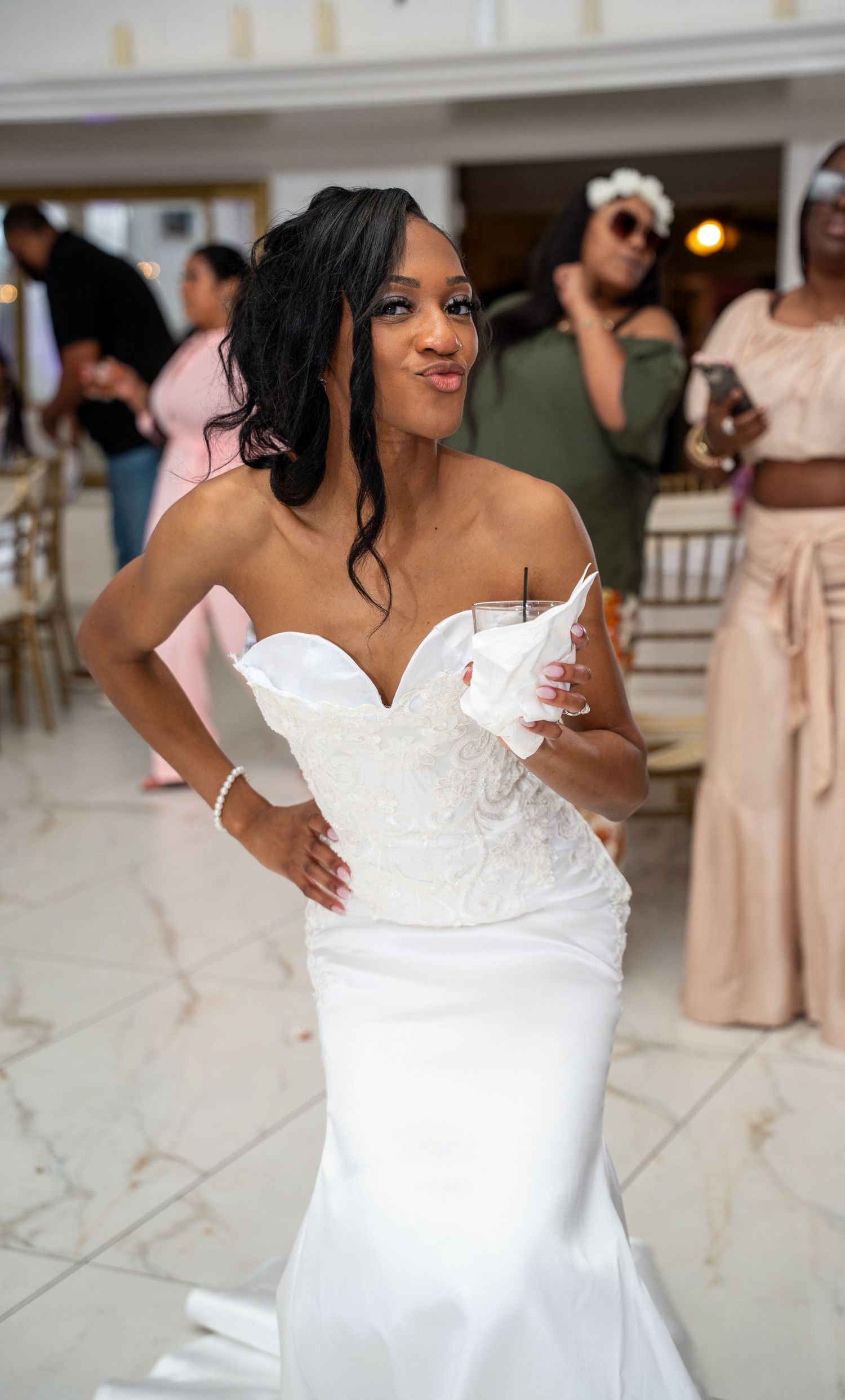 Bride in strapless white mermaid wedding gown holding a drink at her wedding reception.