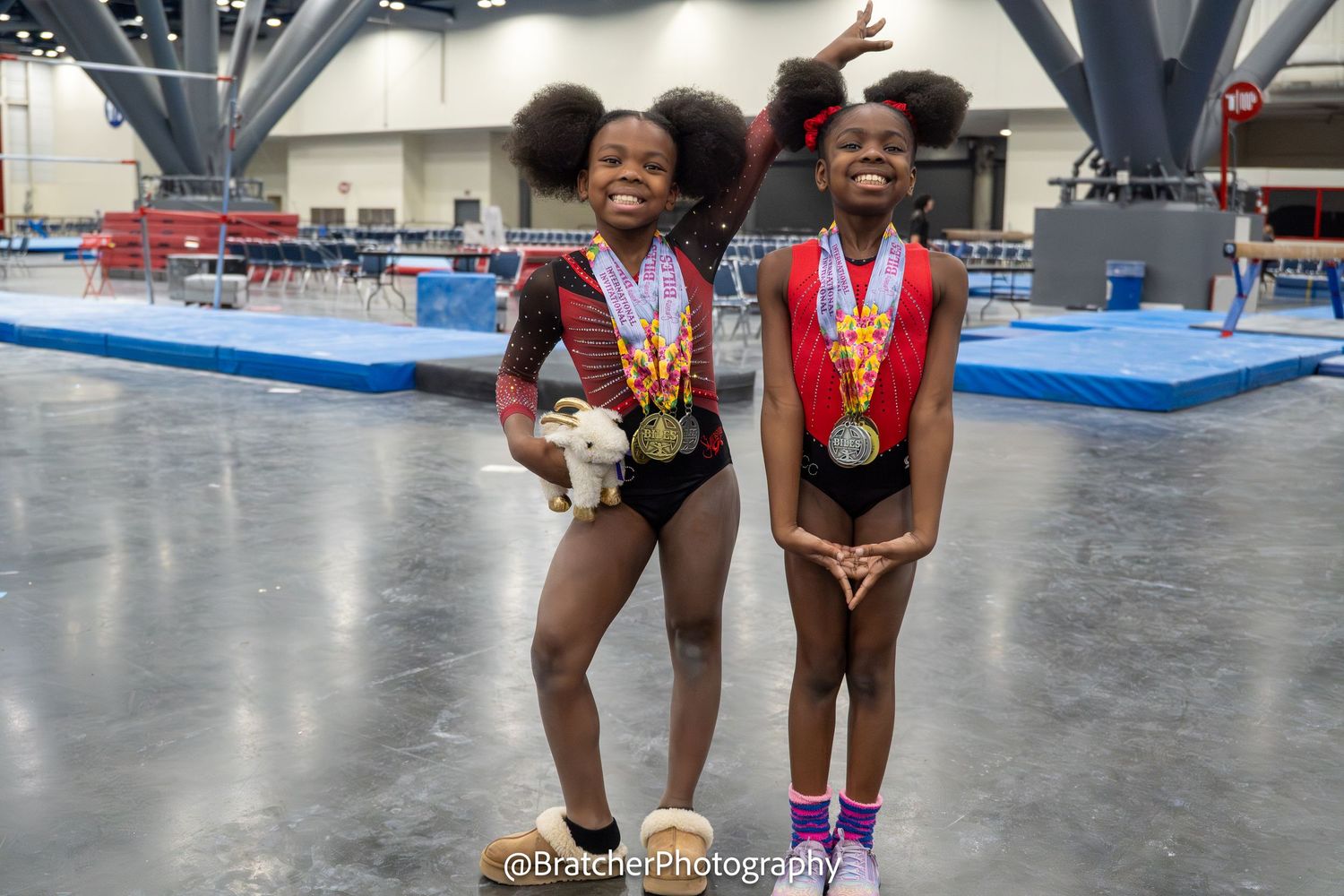 Two young gymnasts pose together proudly displaying their medals at gymnastics meet. bratcher photography and houston photographer