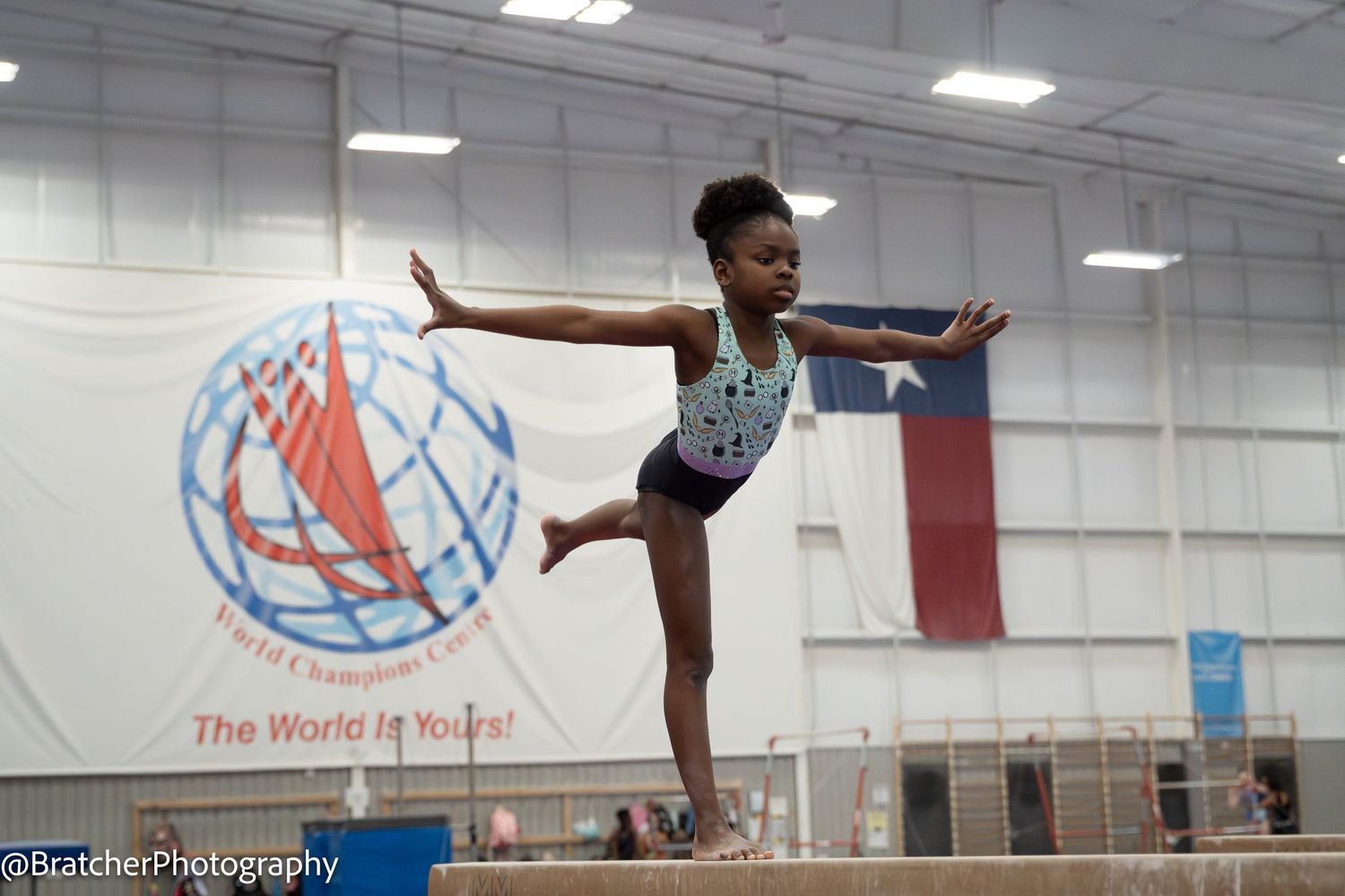 Young gymnast performs arabesque on balance beam at World Champions Centre gymnastics facility in Texas. bratcher photography and houston