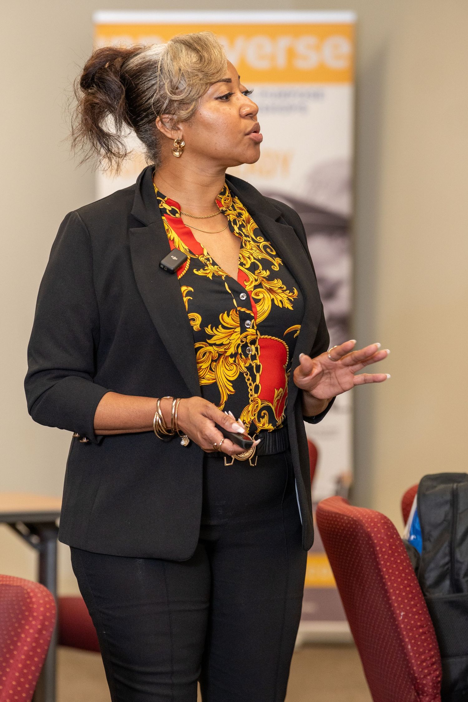 Woman in black blazer and floral top presenting at a business conference event.
