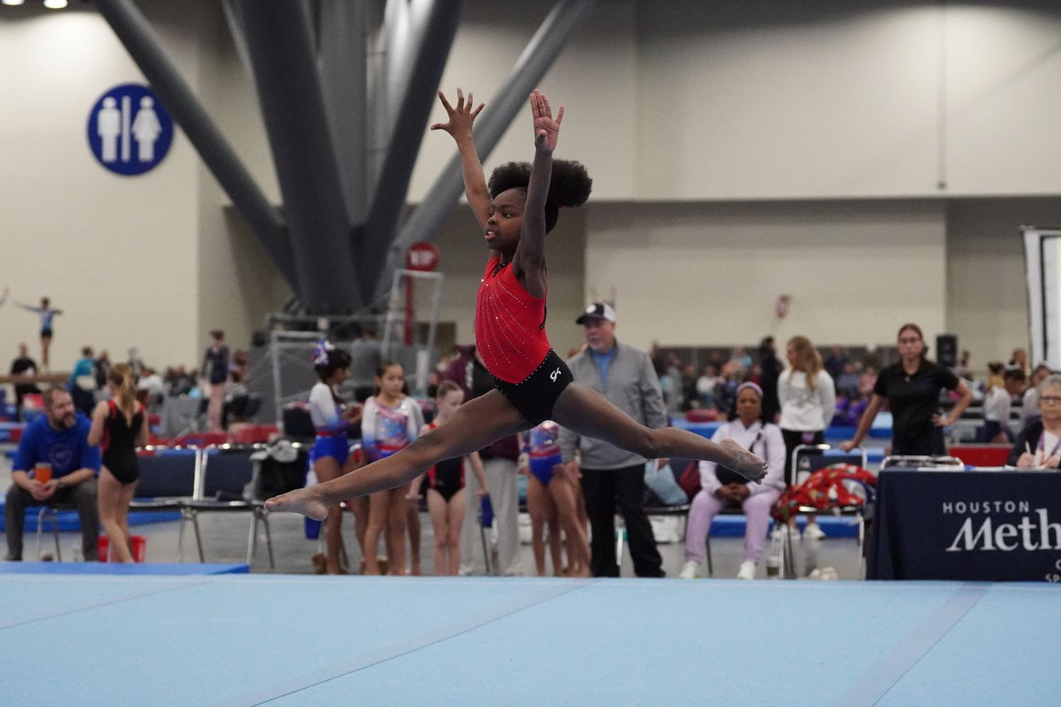 Young gymnast performs leap on floor exercise at Houston gymnastics competition. bratcher photography and houston photographer