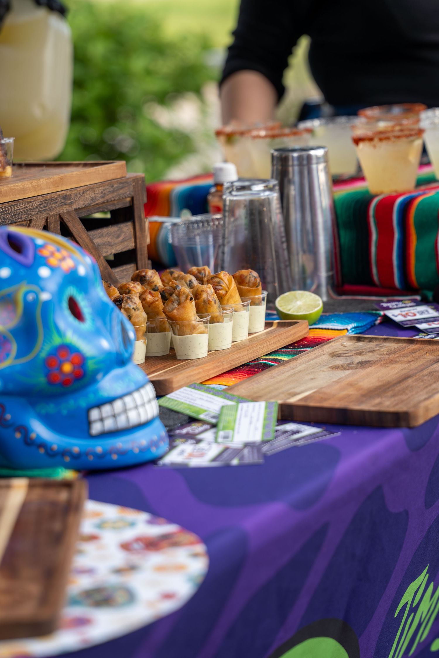 Colorful Day of the Dead sugar skull decorates Mexican food tasting table with mini appetizers.