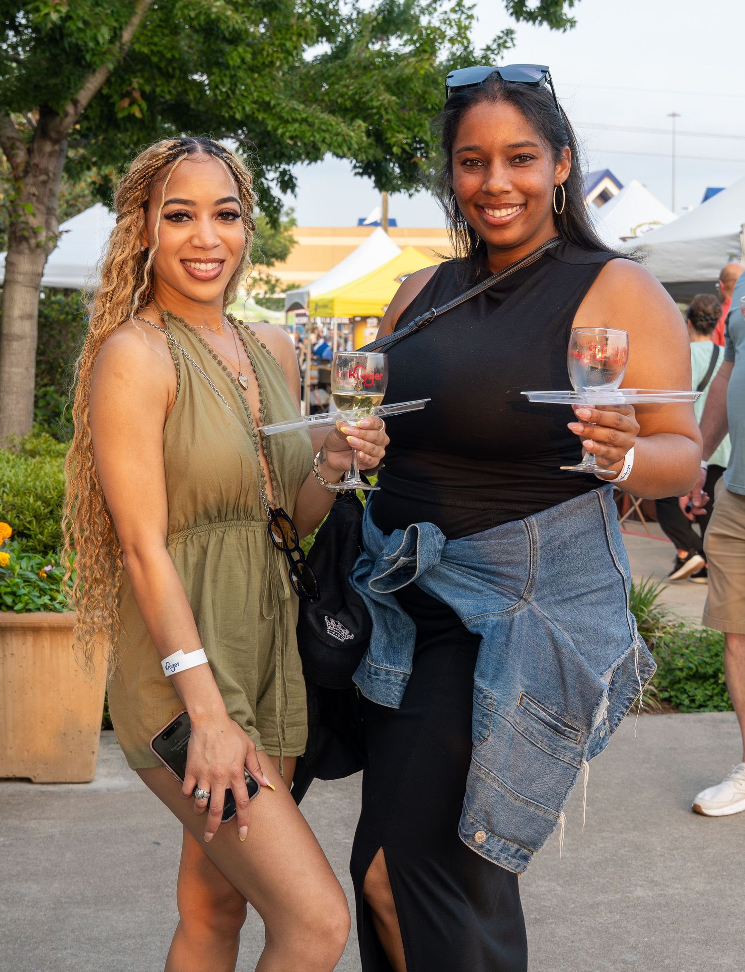 Two women smile and hold drinks at outdoor food and wine festival. bratcher photography and houston photographer