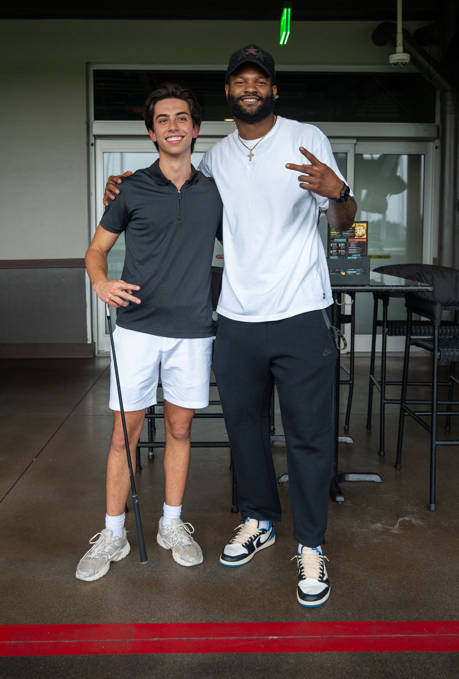 Two young men posing together smiling at an outdoor golf venue.
