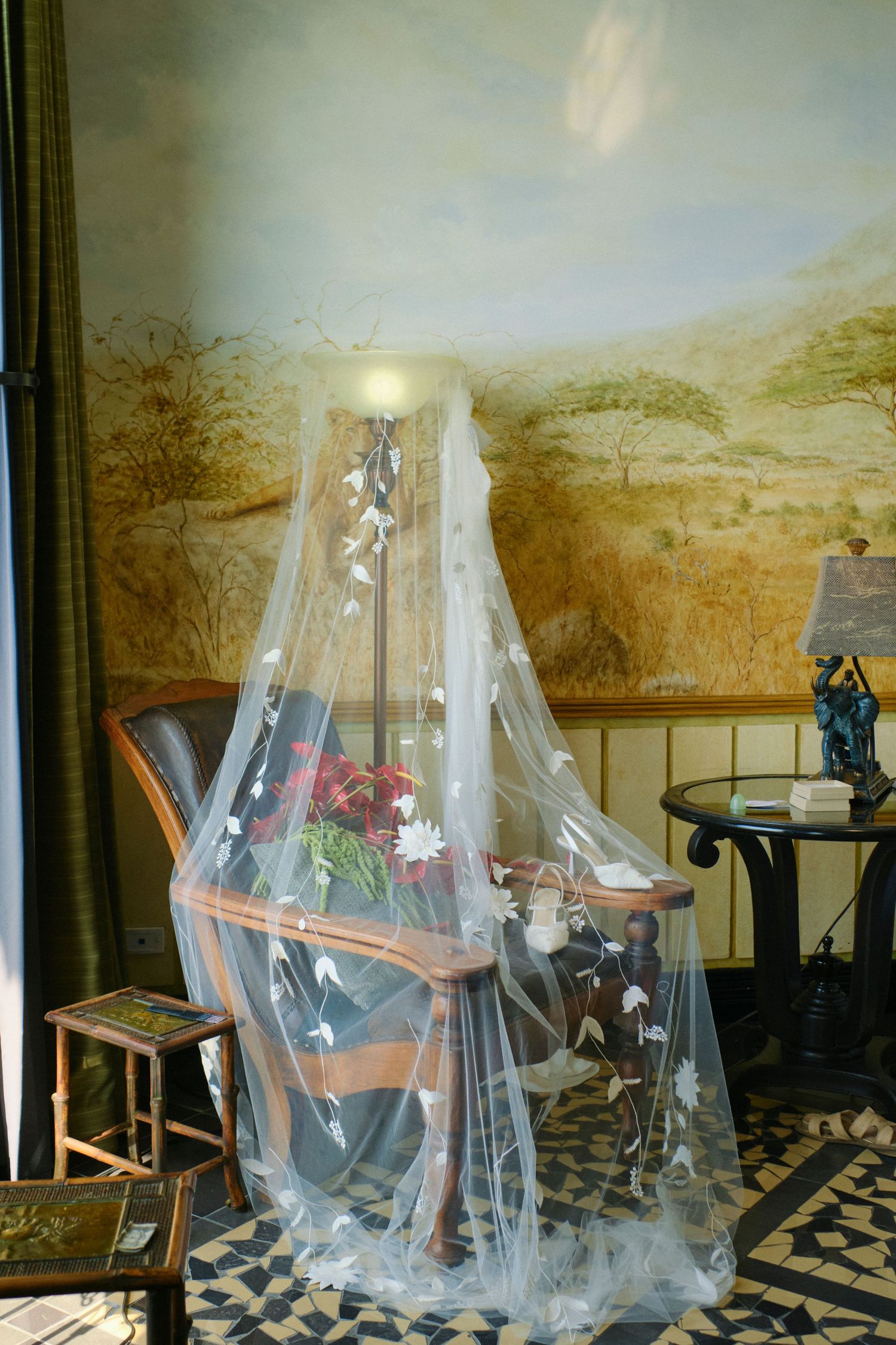 Floral wedding veil draped over a chair in an elegantly decorated safari-themed bridal suite.